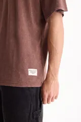 Remera oversize de manga corta raglán, color negro con efecto lavado acid wash, corte semi boxy y detalle de etiqueta lateral en el ruedo.