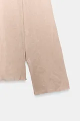 Jersey de punto de manga larga en color beige rosado, con cuello alto drapeado y diseño con efecto arrugado.