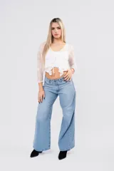 Blusa de encaje floral blanco con transparencias, mangas largas, escote cruzado y lazos frontales con volados.