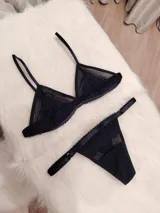 Conjunto de lencería compuesto por un corpiño triangular de microtul transparente con detalles de encaje en las copas y una tanga regulable de elástico ancho.