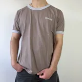 Remera marrón con ribetes grises en el cuello redondo y en los puños, de corte regular y manga corta. Cuenta con un pequeño estampado con la inscripción "Midway" en el pecho.