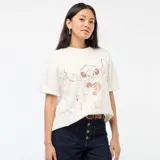 Camiseta de cuello redondo y manga corta, color blanco hueso, con estampado central metalizado en tono oro rosa del personaje Stitch sosteniendo un corazón.