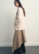 Abrigo corto de corte recto y diseño cruzado, confeccionado en tejido mezcla de lana. Presenta cuello con solapas de muesca, cierre frontal con botones oscuros y dos bolsillos laterales. Cuenta con forro interior y mangas largas.