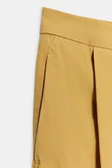 Jeans de tiro bajo y corte wide leg, color amarillo mostaza, con pliegues frontales, bolsillos ocultos y cierre frontal con cremallera, botón y ganchos metálicos.