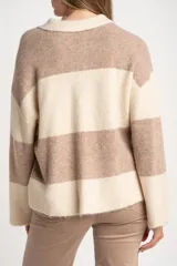 Sweater de punto con cuello polo y cierre frontal de tres botones. Presenta un diseño de corte oversize, mangas largas y textura acanalada.