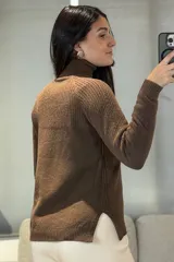 Buzo de punto con cuello alto, diseño de textura acanalada en el frente y mangas largas con puños ajustados.