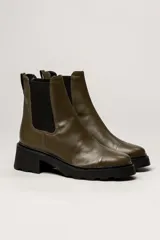 Bota tipo Chelsea de cuero color verde oliva, con paneles laterales elásticos negros y suela track de goma negra con taco cuadrado.