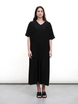 Vestido midi negro con cuello en V, mangas cortas y aberturas laterales. Confeccionado en tejido fluido con un toque de lurex.