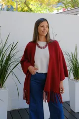 Saco abierto tipo capa en color bordó, confeccionado en tejido de punto suave, con mangas amplias y detalle de flecos en el ruedo.
