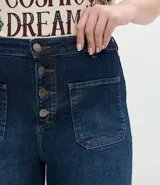 Pantalón de jean modelo flare, de tiro alto, con cierre frontal de botones a la vista y bolsillos funcionales.