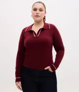 Suéter bordó de punto slim, con cuello polo, mangas largas y puños canelados. Presenta detalles de rayas contrastantes en color blanco en el cuello y en los puños.