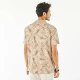 Remera tipo polo color beige con estampado de hojas en tonos marrones y blancos.