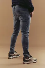 Jeans ajustados de mezclilla azul oscuro, corte skinny, con efecto desgastado y costuras decorativas en los bolsillos traseros.