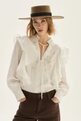 Blusa de algodón color blanco con volados frontales, cuello mao con lazos y detalles bordados en el pecho.