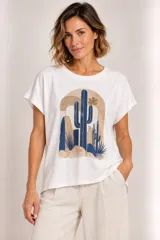 Remera blanca de manga corta, con cuello redondo y diseño holgado, con estampa frontal de cactus en tonos azules y tierra.