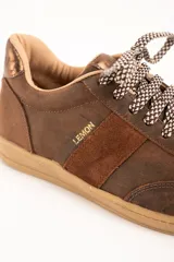 Zapatillas urbanas de cuero color marrón, con cordones estampados en tonos marrones y blancos, y suela de goma al tono. Presentan una franja lateral de gamuza y detalles con la marca en dorado.