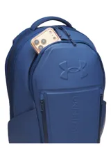 Mochila Under Armour de color azul marino, diseñada con tirantes acolchados y texturizados para mayor comodidad, correa ajustable en el pecho con hebilla y el logo de la marca en relieve.