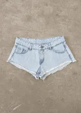 Short de jean tiro bajo color celeste claro, con diseño de corte muy corto y dobladillo desmechado con flecos.