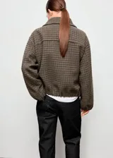 Chaqueta bomber de mezcla de lana con diseño de pata de gallo en tonos marrones y verdes, cuello camisero, manga larga con puños elásticos y bajo elástico. Cuenta con forro interior y cierre delantero con cremallera.