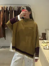 Buzo tejido de silueta amplia con cuello alto, mangas largas con puños en contraste y aberturas laterales en el ruedo. Presenta detalle de bordado en el pecho.