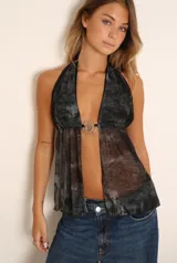 Top halter negro con estampado abstracto en tonos grises, con abertura en el frente unida por un aro metálico.
