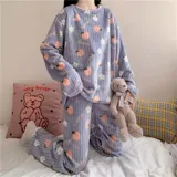Conjunto de pijama de dos piezas confeccionado en plush suave, compuesto por una remera de manga larga y pantalón largo. Presenta un diseño estampado de duraznos sobre fondo color crema.