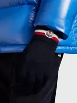 Guantes de lana color azul marino con puños acanalados a rayas blancas y rojas, y logo de Moncler en el dorso de la mano.