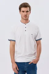 Remera blanca de manga corta con cuello mao y cierre frontal parcial con tres botones. Presenta detalles en color azul en el cuello y en los bordes de las mangas, además de un pequeño logo bordado en el pecho.