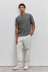 Remera de algodón color marrón con efecto lavado, de corte clásico y cuello redondo. Presenta un pequeño bordado de un pájaro en el pecho.