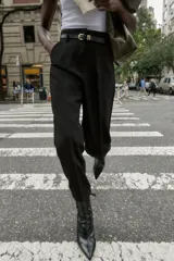 Pantalón de tiro alto y corte tobillero, confeccionado en tejido de aspecto denim oscuro. Presenta diseño de pinzas frontales, bolsillos laterales y cierre frontal con cremallera, botón y gancho. Incluye un cinturón fino a tono con hebilla metálica dorada.