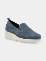 Zapatilla slip-on de mujer color azul, con plataforma tipo cuña de color crema. La capellada es de material liso y perforado en la zona del empeine.