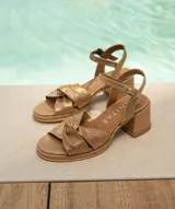 Sandalias de cuero color dorado, con plataforma y taco cuadrado. Presentan tiras cruzadas en el empeine y pulsera al tobillo con hebilla.
