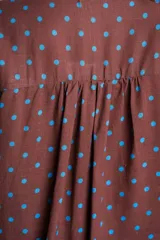 Blusa color crudo con estampado de lunares marrones, cuello camisero, cierre frontal con botones y mangas cortas holgadas.