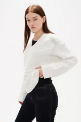 Sweater de punto color natural, con cuello en V, manga larga y diseño holgado con textura acanalada horizontal.
