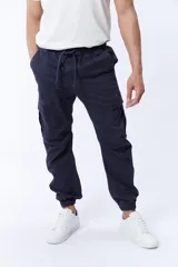 Pantalón cargo estilo jogger color azul marino con cintura elástica ajustable con cordón, bolsillos laterales y bolsillos cargo con solapa en los muslos. Tobillos elastizados.