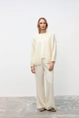 Cardigan abierto de punto color crudo, con mangas largas y corte holgado.