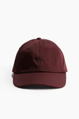 Gorra color borgoña de sarga de algodón con ojales bordados y correa ajustable con hebilla metálica en la parte trasera.