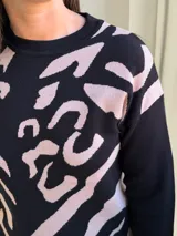 Sweater de tejido de punto con diseño estampado abstracto en tonos negro y beige, de cuello redondo y manga larga.