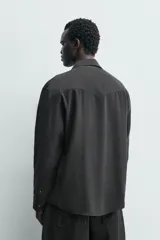 Camisa de corte regular confeccionada en tejido fluido con mezcla de lyocell, cuello solapa, manga larga con puños abotonados y cierre frontal de botones.