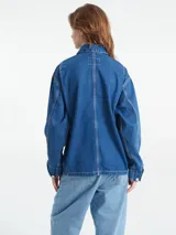 Campera de trabajo tipo chore coat Carhartt modelo Michigan, confeccionada en denim negro con costuras en contraste. Presenta cierre frontal con botones metálicos grabados, cuello clásico y cuatro bolsillos frontales, uno de ellos con etiqueta de la marca.