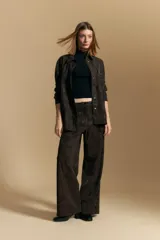 Pantalón de corte ancho y silueta relajada, confeccionado en tejido de efecto gamuzado color marrón oscuro. Presenta un diseño de tiro alto con cierre frontal y bolsillos laterales.