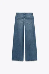 Jeans de tiro bajo, pierna ancha y largo completo, color negro. Presenta cinco bolsillos y cierre frontal con cremallera y botón metálico.