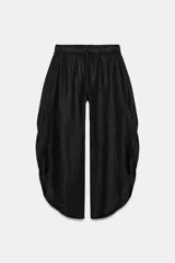 Pantalón de tiro medio confeccionado en lino, con cintura elástica ajustable mediante cordones. Presenta un diseño de pernera ancha con bajo redondeado y aberturas laterales.