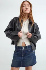 Campera bomber de manga larga confeccionada en tejido efecto cuero. Presenta un diseño con cuello clásico, cierre frontal con cremallera y bajo con detalle abullonado.