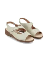 Sandalias de cuero color crema, con tira ajustable con velcro en el empeine, talón cerrado con tira elástica y suela de plataforma baja marrón.