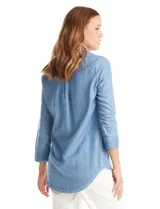 Blusa de lyocell color azul con efecto denim, cuello camisero con solapa y escote en V con cierre de un botón. Presenta mangas largas con terminación doblada y ruedo redondeado.