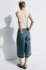 Bermuda larga de jean color azul, tiro medio, con diseño wide leg y bolsillos. Cuenta con bajo desflecado y cierre frontal con cremallera y botón metálico.