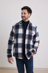 Sobrecamisa de hombre con diseño a cuadros en tonos marrón, beige y blanco. Confeccionada en tejido peludito suave, con cuello clásico, cierre frontal con botones, bolsillo superior y mangas largas con puños abotonados.