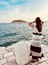 Vestido largo tejido a rayas horizontales en tonos blanco, beige y negro, de corte recto y sin mangas.