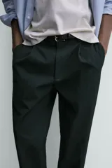Pantalón de corte regular fit confeccionado en tejido mezcla de algodón. Presenta cintura con detalle de pliegues en el delantero, bolsillos frontales y bolsillos traseros de vivo con botón. Cierre frontal con cremallera y botón.